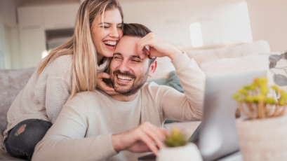 Queensland couple looking happy at FHOG on laptop
