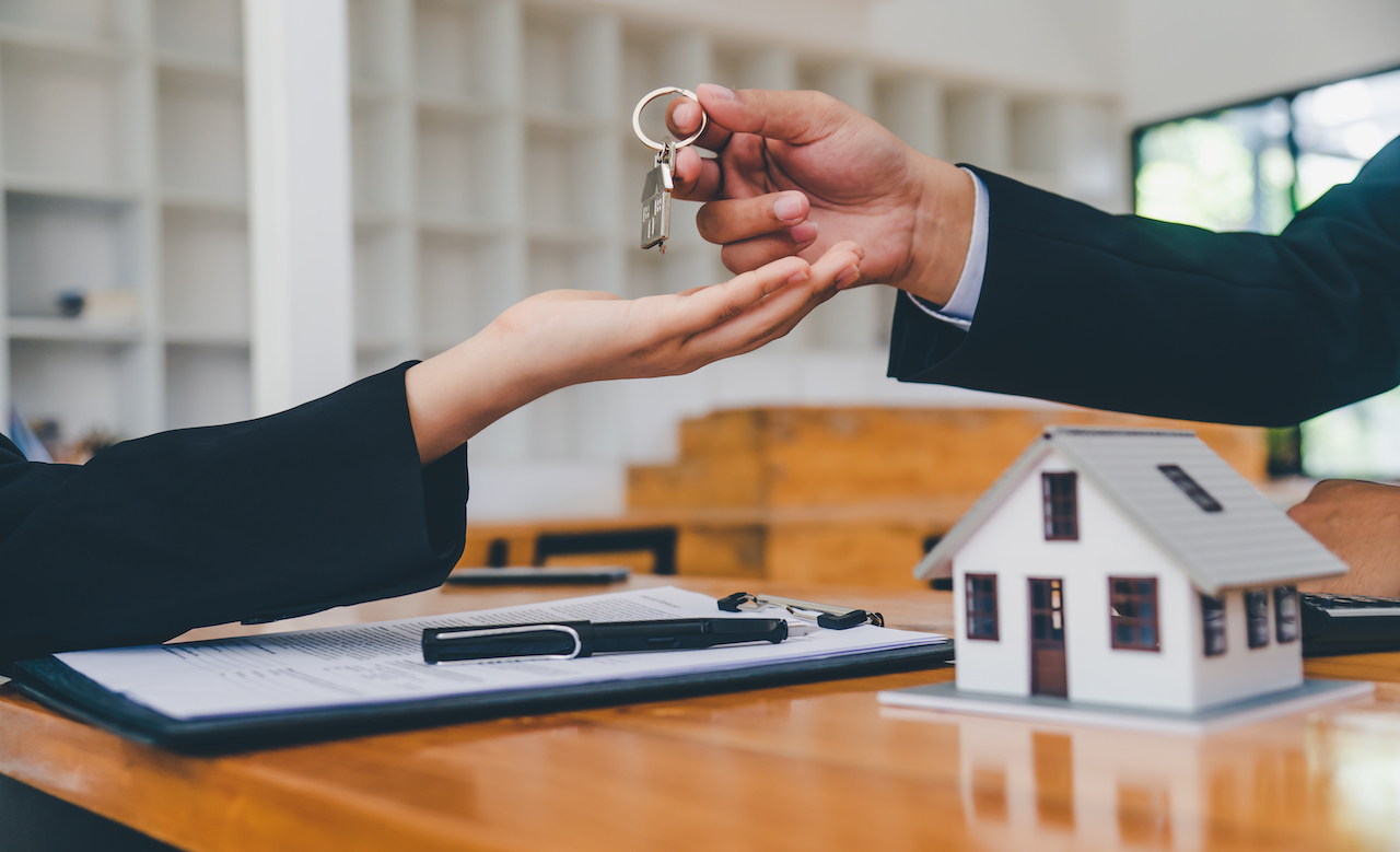 Salesperson Concept Of Holding House Keys, House Keys For A New Home, New Home Purchase. A Loan Agreement For Real Estate, A Loan Deal For Real Estate, A Loan Agreement For Real Estate